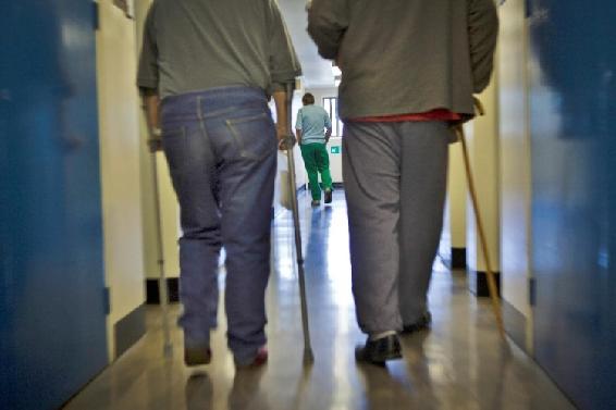 Dos internos adultos mayores con bastones caminan por un pasillo.