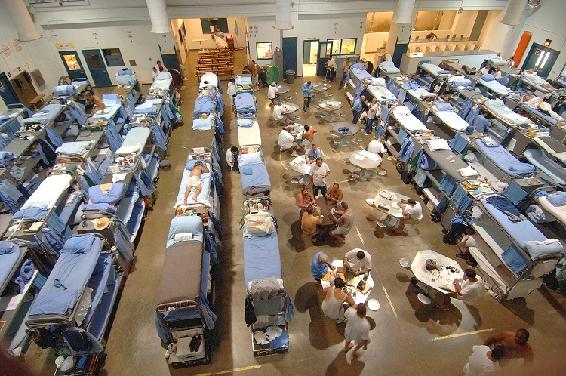 photograph of an overcrowded California prison. The Dining area has been filled with bunk beds. 