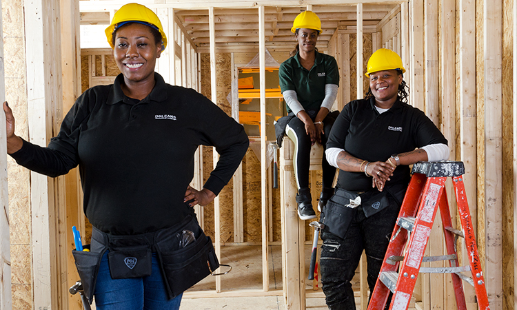 Black women in construction standing in the framework of a building