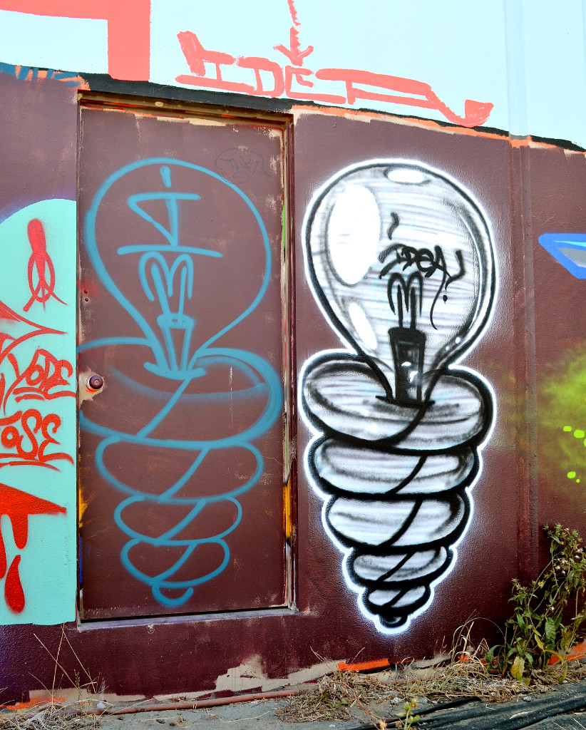 Photo of colorful graffiti on a door and wall, showing two lightbulbs and the word "IDEA."