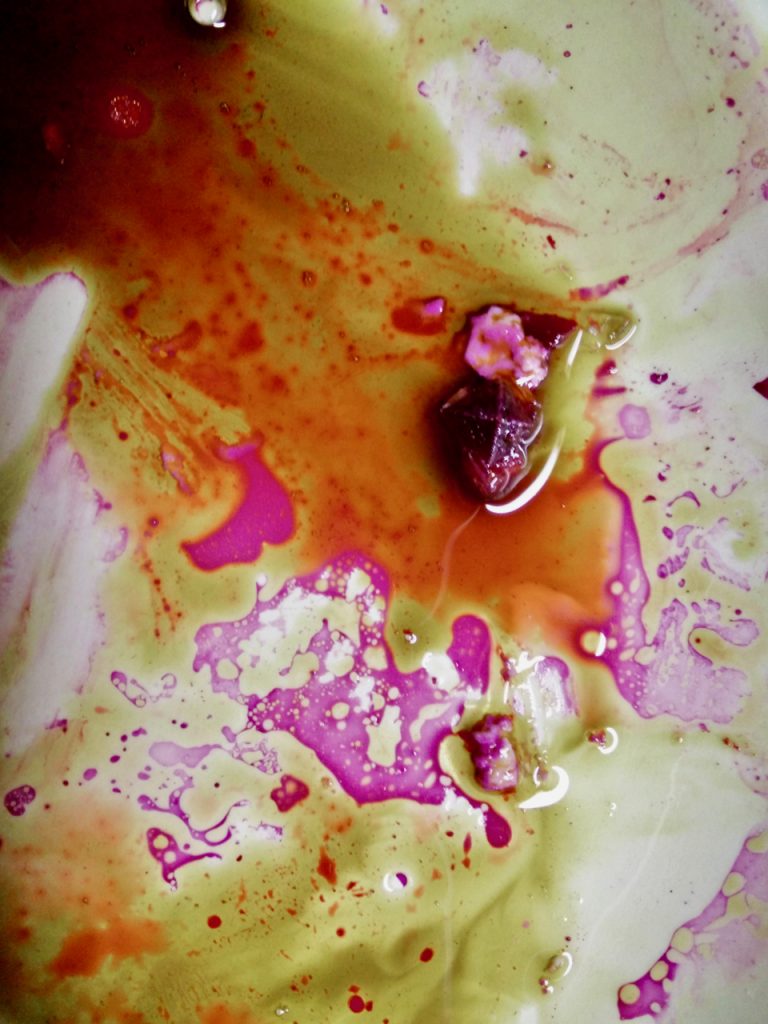 a close up of a plate with multi-colored liquids and traces of food