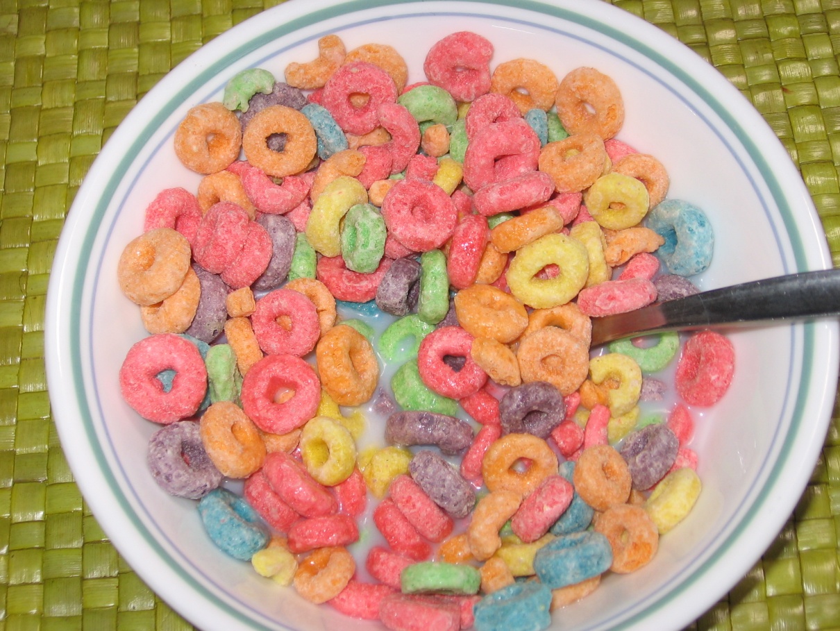 a close up of a bowl full of multi-colored cereal with milk and a spon