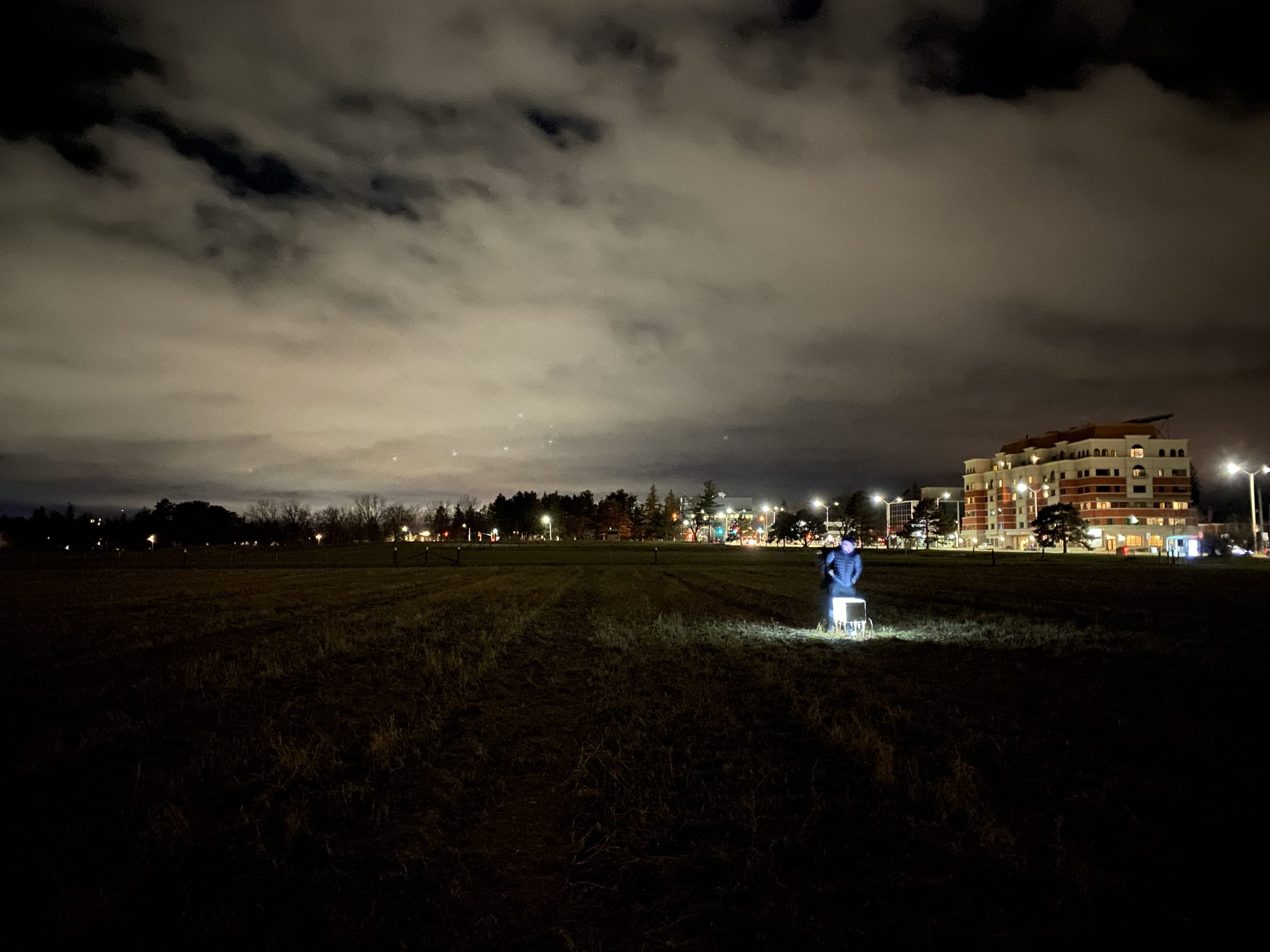 night-time view of a field with a glowing art installation at the centre