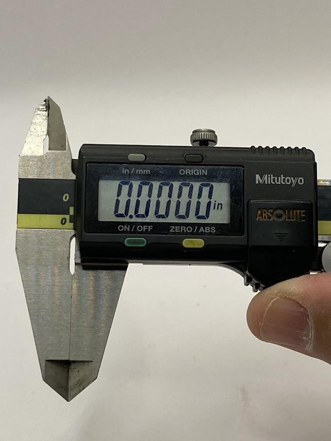 A digital slide caliper is closed and the display indicates zero.