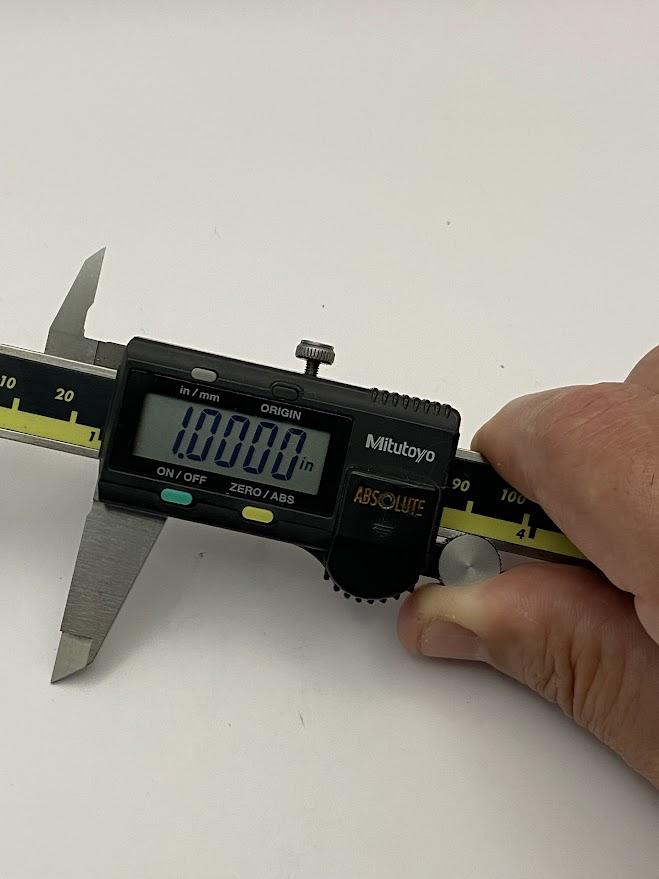 An operator placing the slide micrometer at one inch using the thumb wheel.