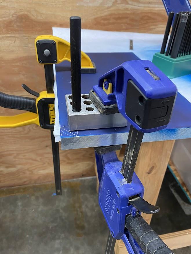 A tap guide clamped to the surface of a workpiece with a transfer punch providing alignment with a center punch mark.