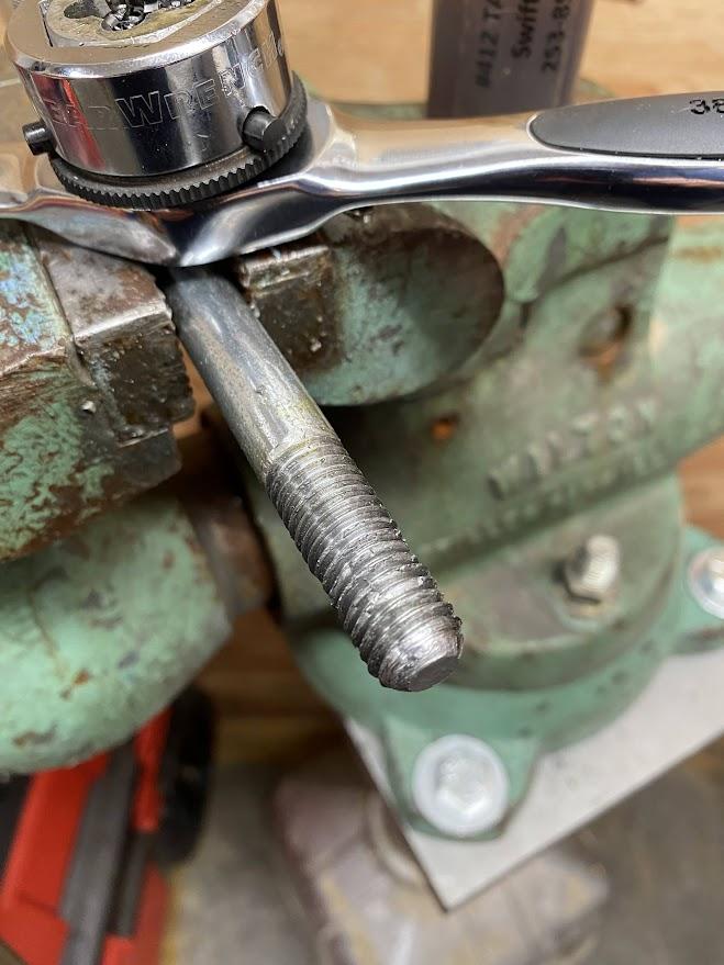 A threaded steel bar clamped in a vise.