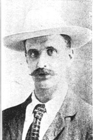 Black and white portrait of a man wearing a wide-brimmed hat, suit, and tie, with a prominent mustache.