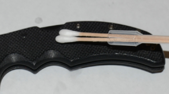 swabbing the knife handle with the cotton swabs held in the applicator