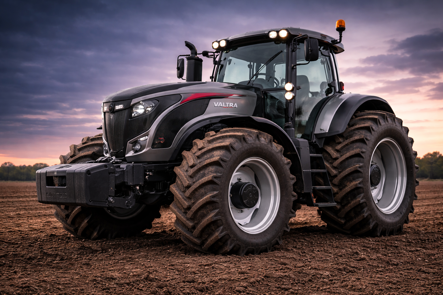 A modern Valtra tractor parked on freshly tilled soil, with an overcast sky and trees in the background at sunset.