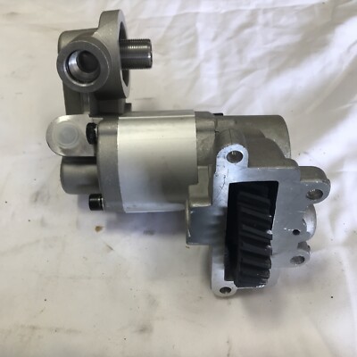 A silver automotive oil pump with gear mechanism against a white background.