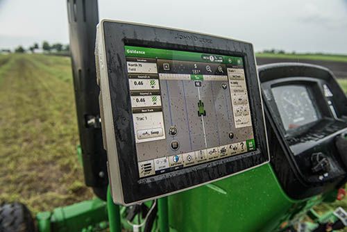 Close-up of a digital display mounted on a tractor, showing farming controls and navigation options.