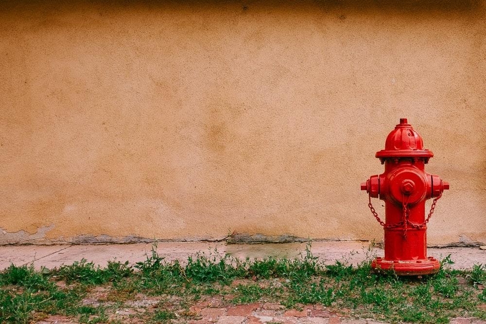 A red fire hydrant next to a wall in Santa Fe