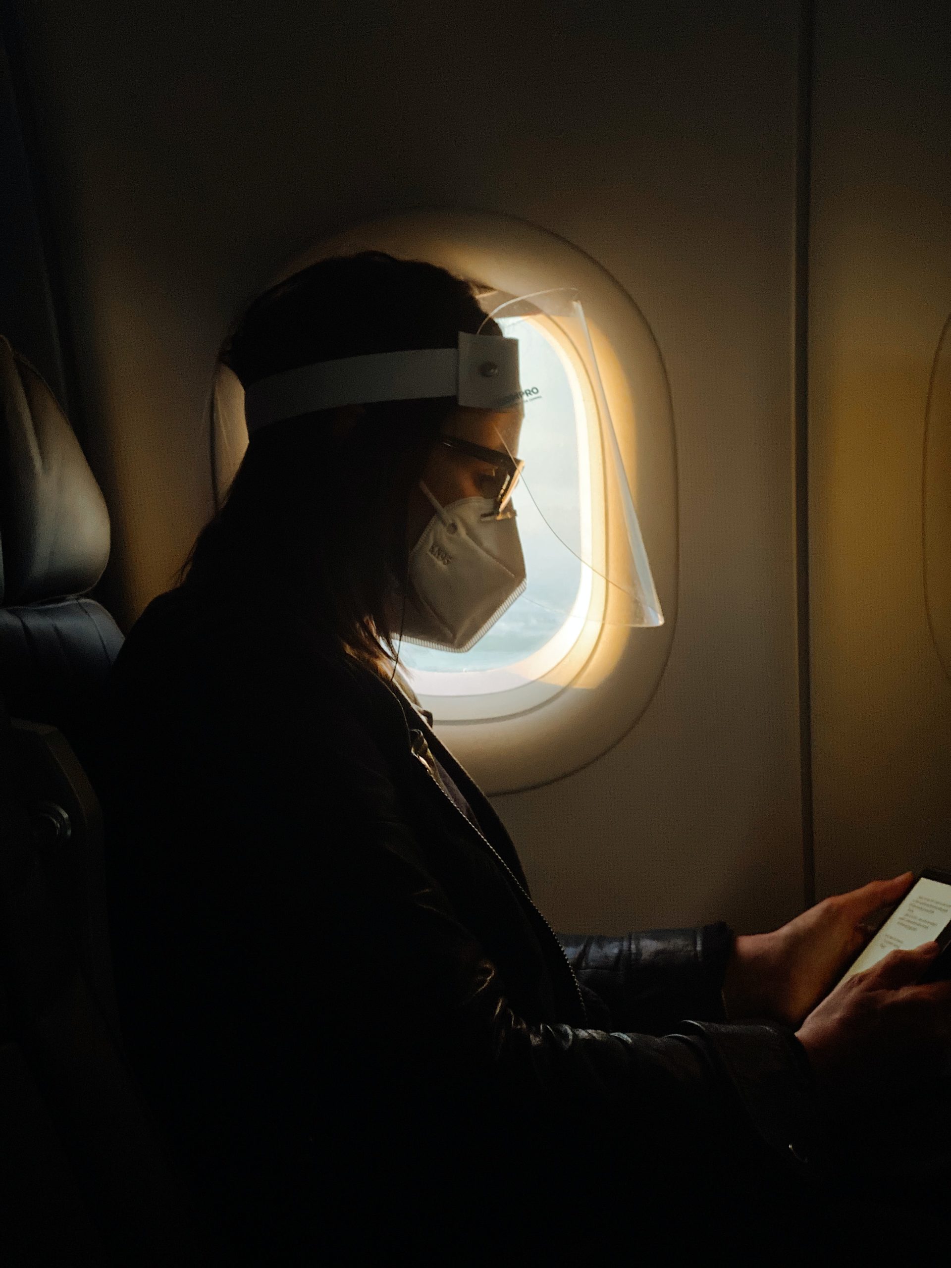 Un pasajero del avión usa una máscara facial y un protector facial.