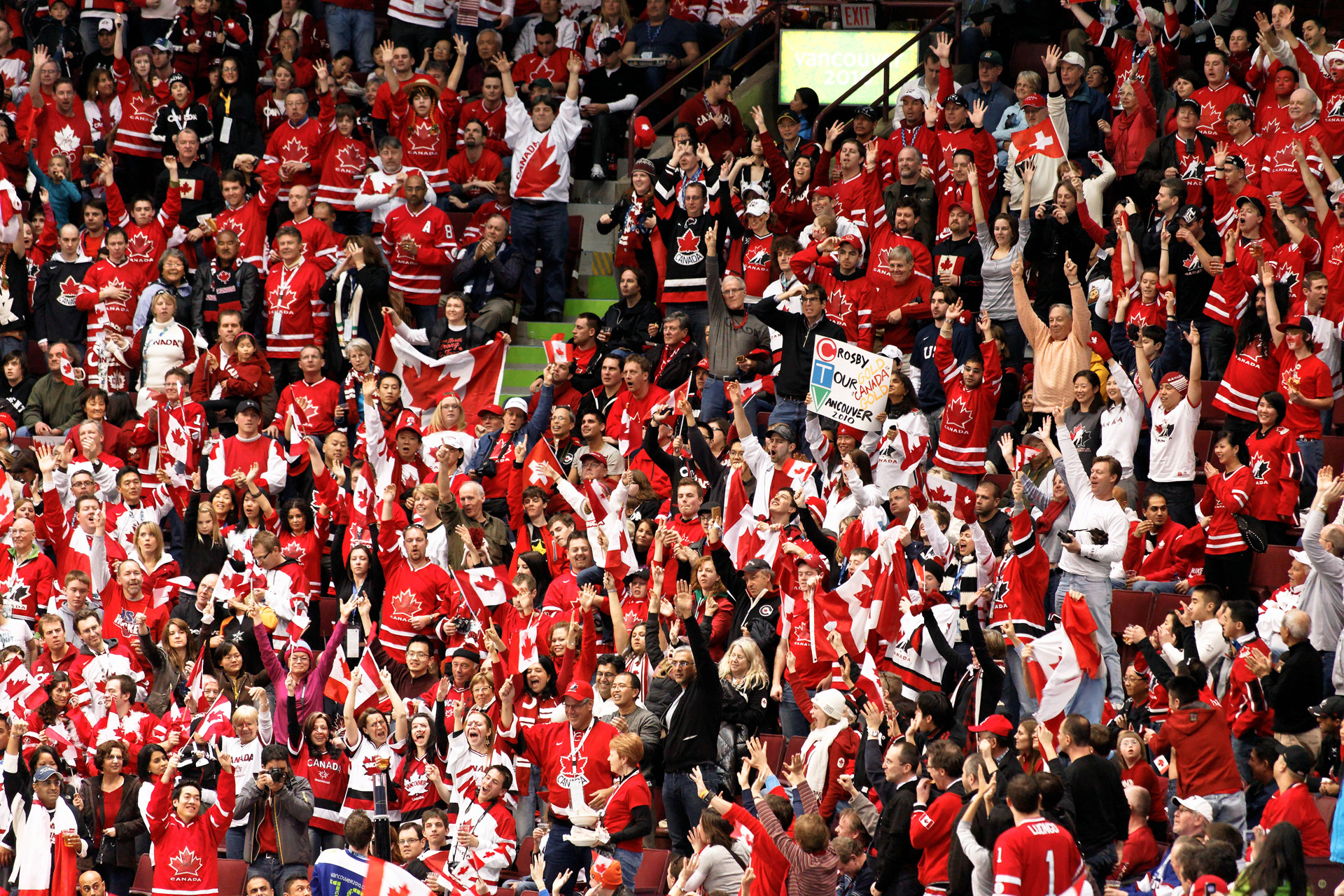 Una multitud de personas vestidas con camisetas canadienses rojas y blancas animan desde los asientos de la arena.