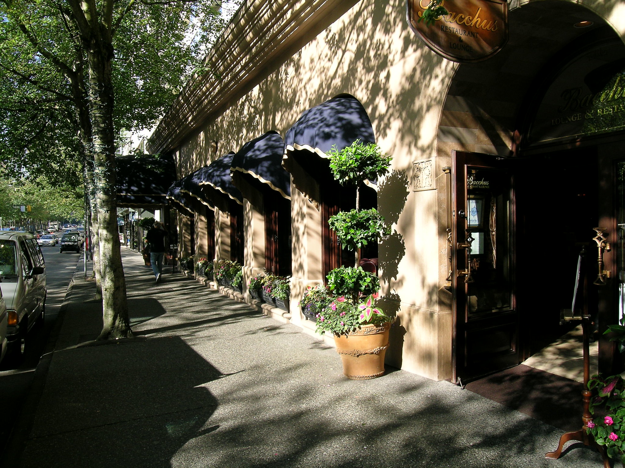 La entrada a un restaurante del hotel llamado Baco, a la sombra de árboles que bordean la calle.