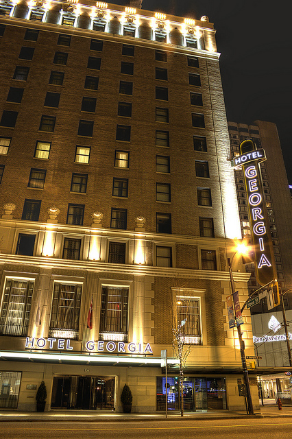 El frente de un hotel histórico por la noche. Un letrero de neón dice “Hotel Georgia”.