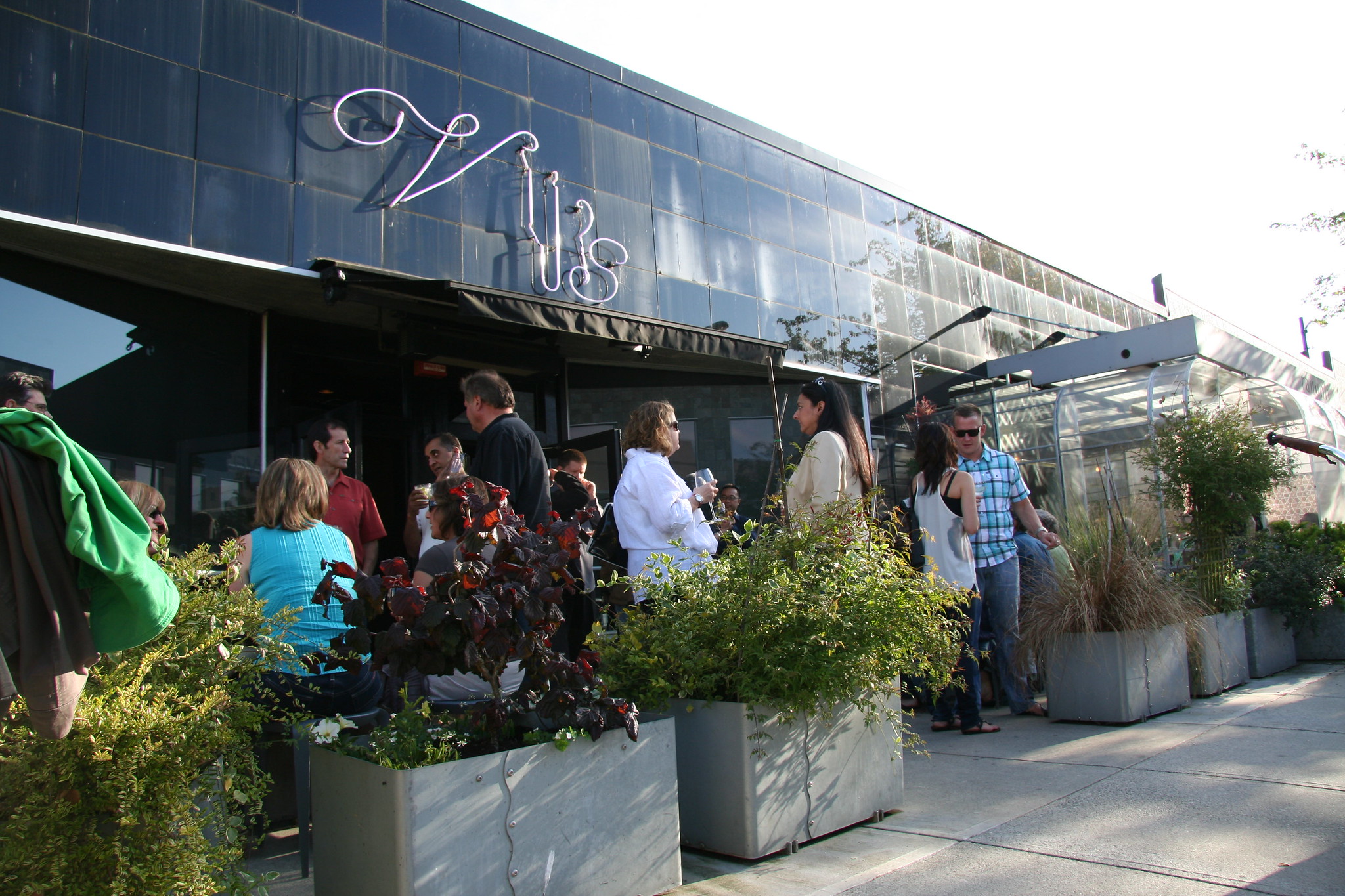 Mucha gente hace fila fuera de un restaurante moderno y elegante.