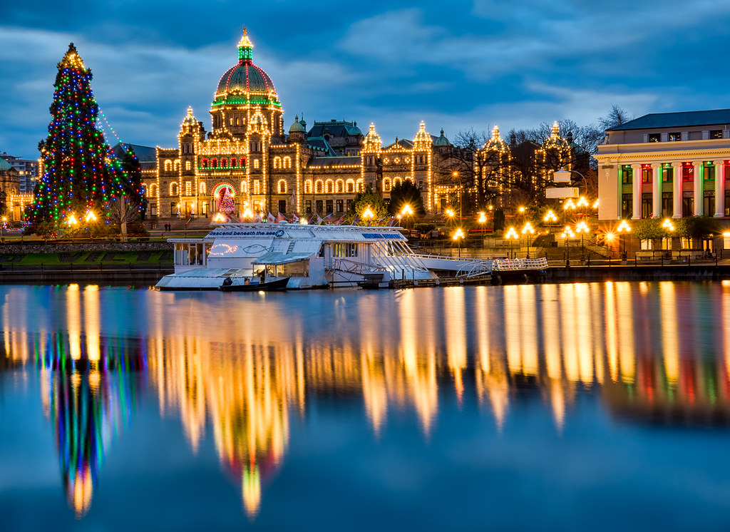 The Christmas lights covering the parliament buildings reflect in the Victoria harbour at dusk.