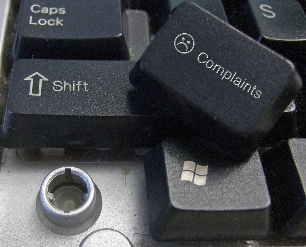 Un teclado con una tecla quitada, que está marcada con una cara triste y la palabra “quejas”.