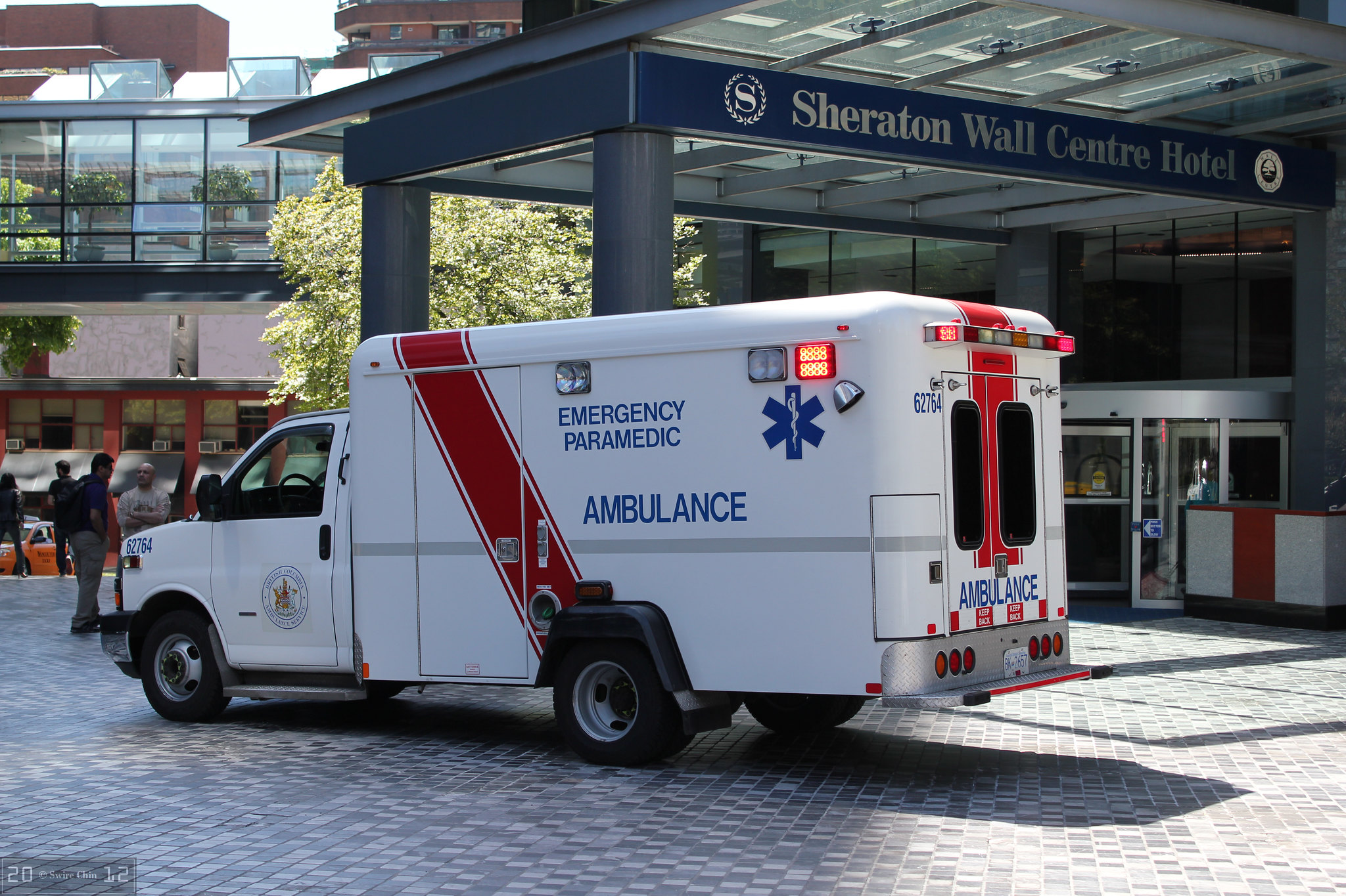 Una ambulancia estacionada afuera de la entrada techada del hotel.