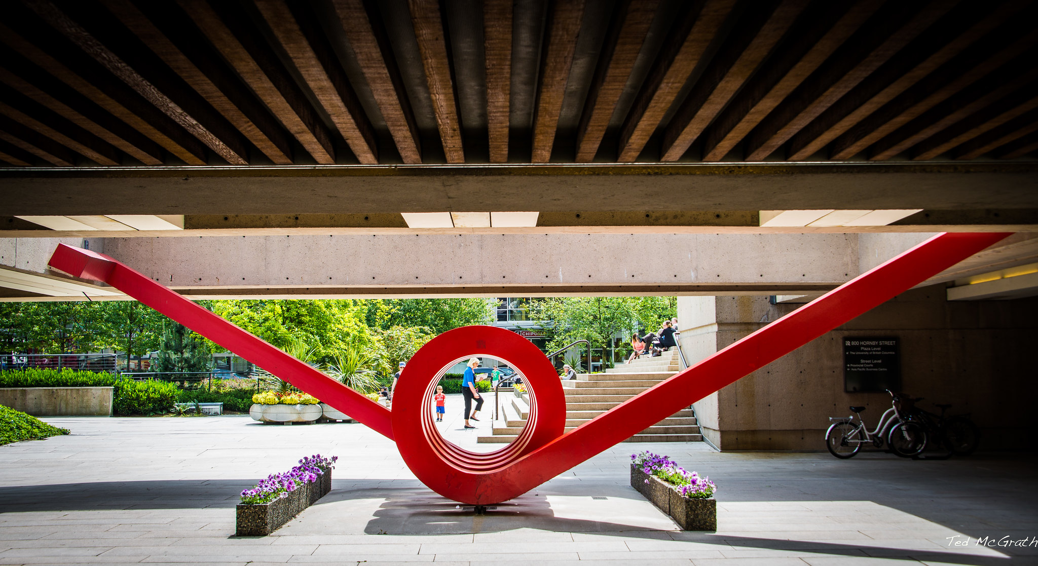Una escultura de metal rojo con un túnel primaveral y dos brazos sobresaliendo en ángulos amplios.