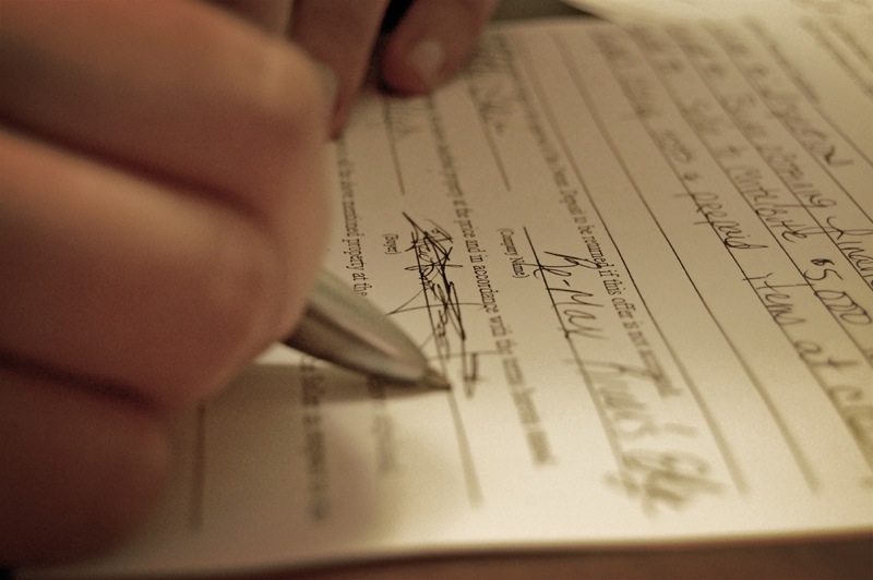 A close-up of a hand signing a contract.