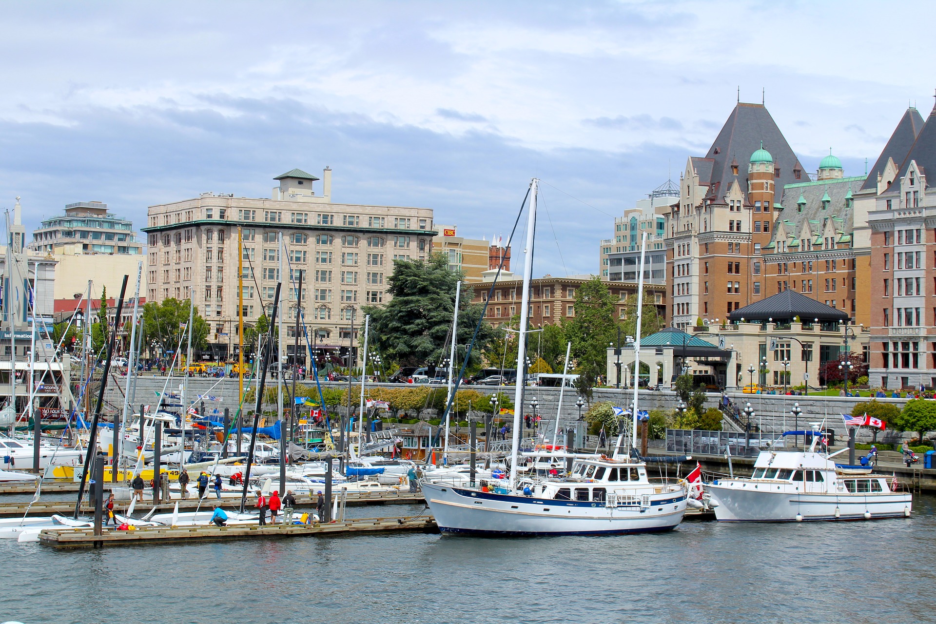 A harbour filled with yachts. Close behind are a city street and a grand hotel.